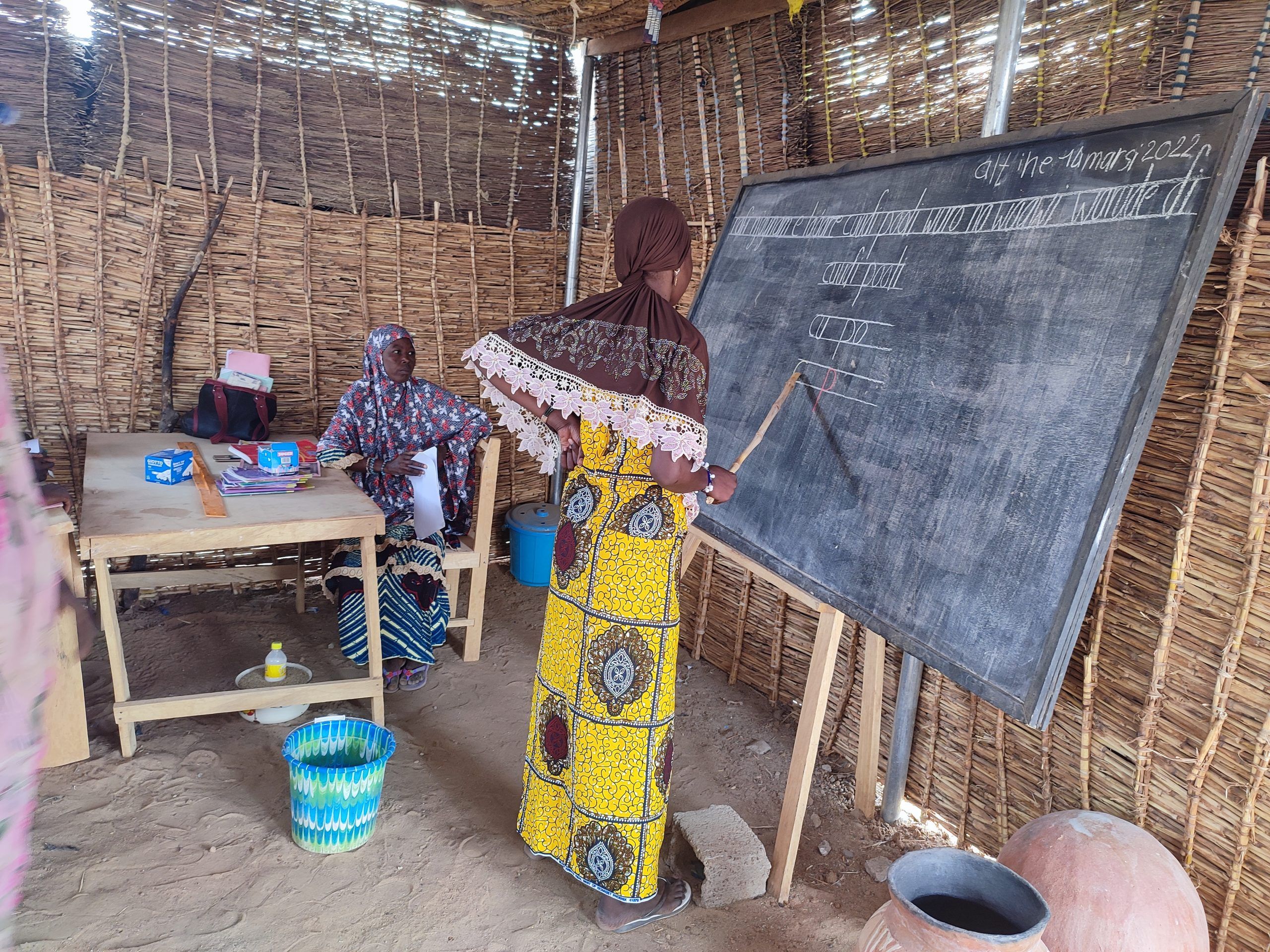Une apprenante et son enseignant pour la lecture au tableau projet d'alphabétisation des femmes PDI
